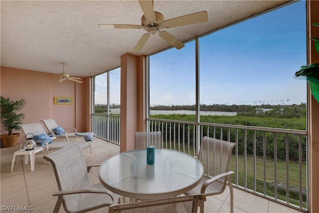 sunroom with a water view and ceiling fan