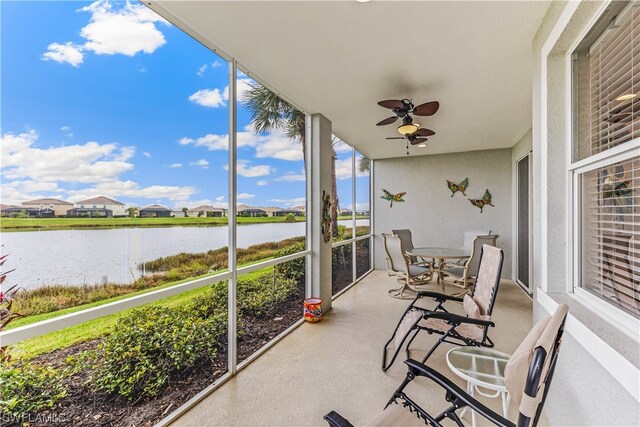 sunroom featuring ceiling fan and a water view