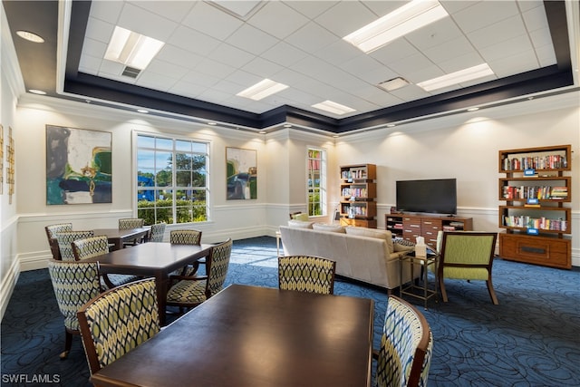 dining space with a tray ceiling, ornamental molding, and dark colored carpet