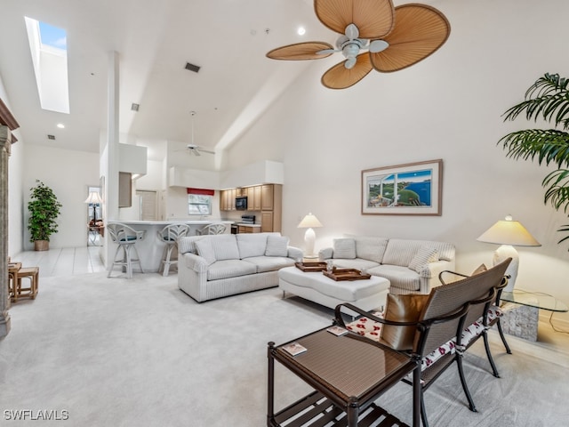 living room with light carpet, a skylight, high vaulted ceiling, and ceiling fan