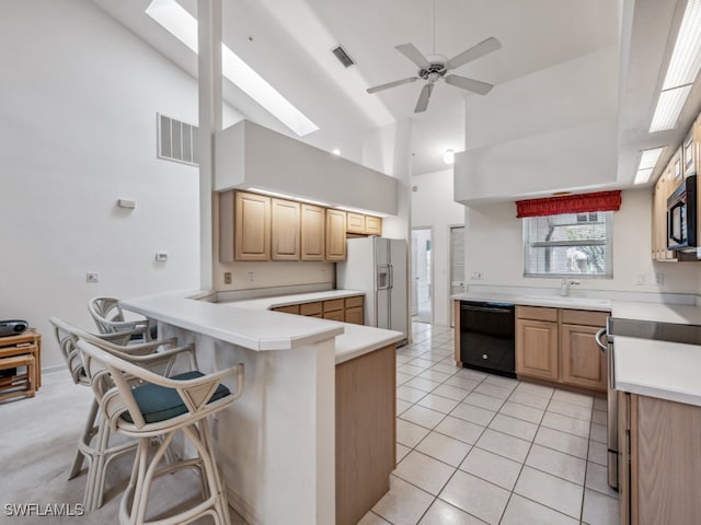 kitchen featuring kitchen peninsula, a kitchen breakfast bar, high vaulted ceiling, and black appliances