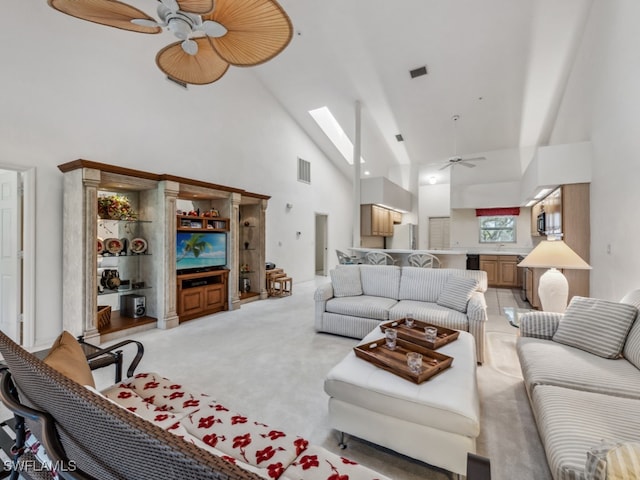 living room with ceiling fan, light carpet, high vaulted ceiling, and a skylight