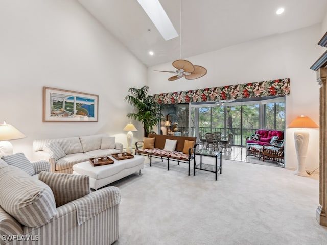 carpeted living room featuring a skylight, ceiling fan, and high vaulted ceiling