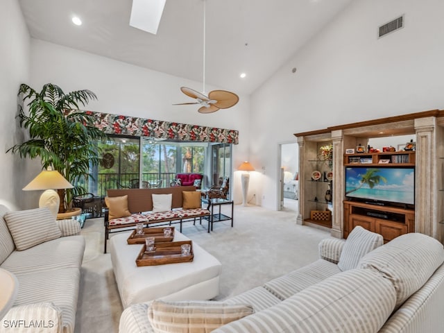 carpeted living room featuring ceiling fan, high vaulted ceiling, and a skylight