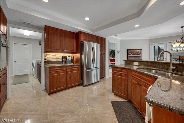 kitchen featuring sink, separate washer and dryer, decorative light fixtures, a tray ceiling, and appliances with stainless steel finishes