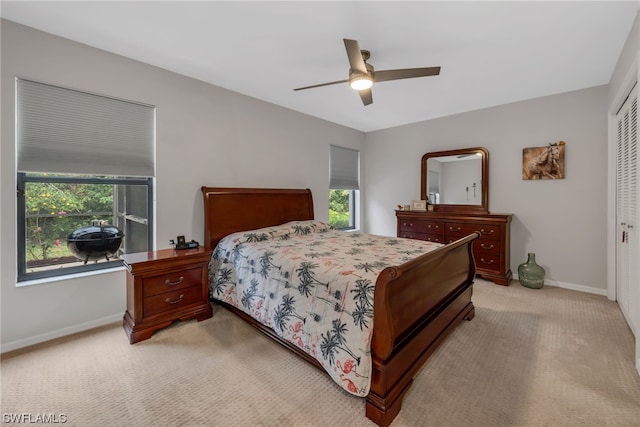 bedroom with multiple windows, ceiling fan, a closet, and light colored carpet