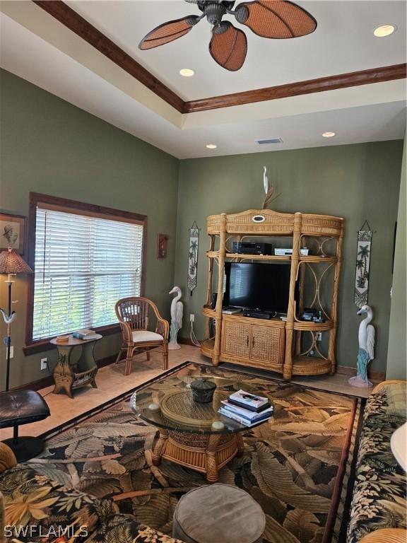 living room with ceiling fan and a raised ceiling