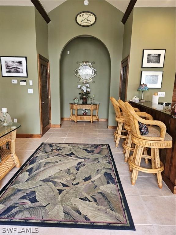 hallway with light tile patterned floors and high vaulted ceiling