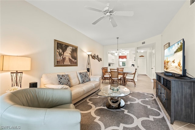 tiled living room with ceiling fan with notable chandelier