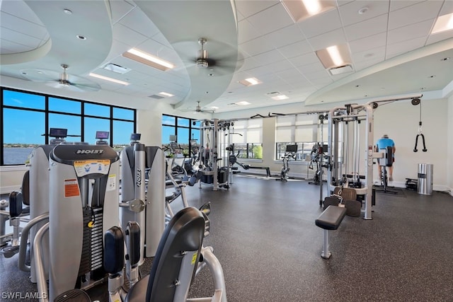 gym featuring a water view, a paneled ceiling, and ceiling fan