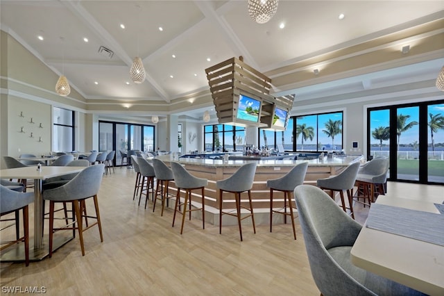 dining space featuring light hardwood / wood-style flooring, beamed ceiling, a healthy amount of sunlight, and a high ceiling