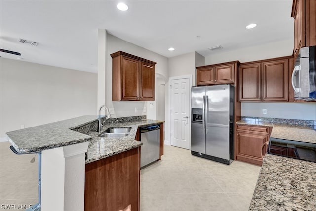 kitchen featuring light tile patterned floors, kitchen peninsula, stainless steel appliances, light stone countertops, and sink