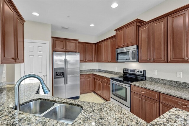 kitchen featuring sink, light stone countertops, and stainless steel appliances