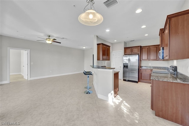 kitchen featuring hanging light fixtures, dark stone counters, ceiling fan, and appliances with stainless steel finishes