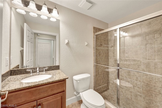 bathroom featuring a shower with door, vanity, and toilet