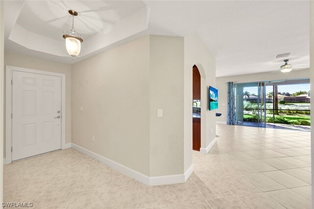 entryway with a raised ceiling and light tile patterned floors