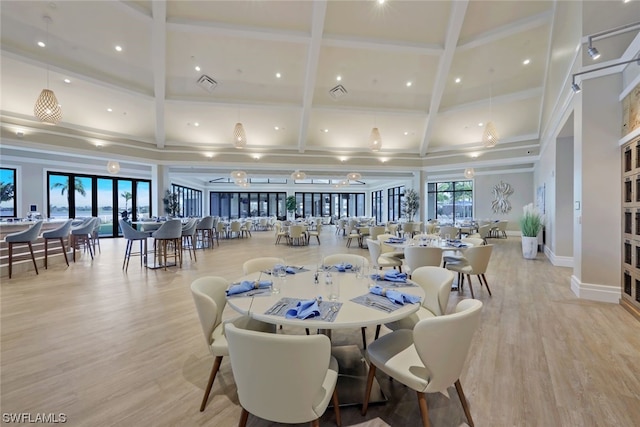 dining area with hardwood / wood-style floors, a towering ceiling, and beamed ceiling