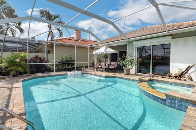 view of pool with glass enclosure, ceiling fan, a patio area, and an in ground hot tub