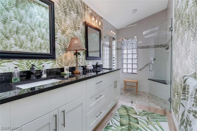 bathroom with a shower with door, vanity, lofted ceiling, and wood-type flooring