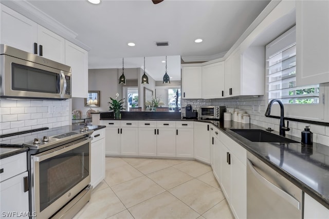 kitchen featuring stainless steel appliances, decorative light fixtures, sink, and white cabinets