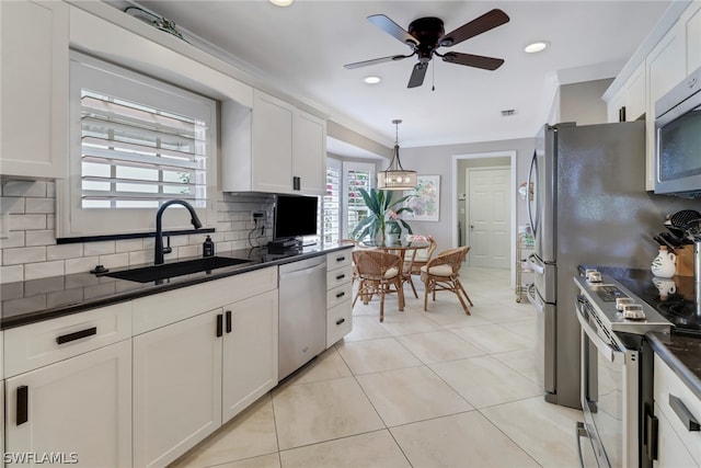 kitchen with appliances with stainless steel finishes, decorative light fixtures, tasteful backsplash, white cabinetry, and sink