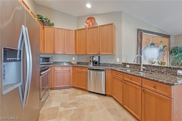 kitchen featuring dark stone counters, stainless steel appliances, light tile floors, and sink