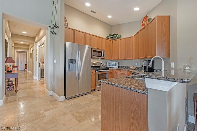 kitchen with stainless steel appliances, sink, light tile floors, and dark stone counters