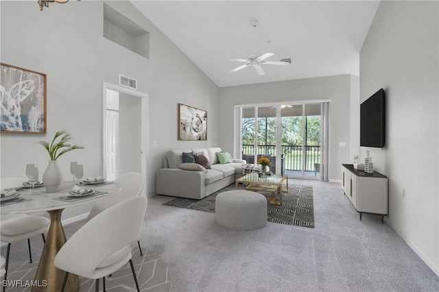 carpeted living room with ceiling fan and high vaulted ceiling