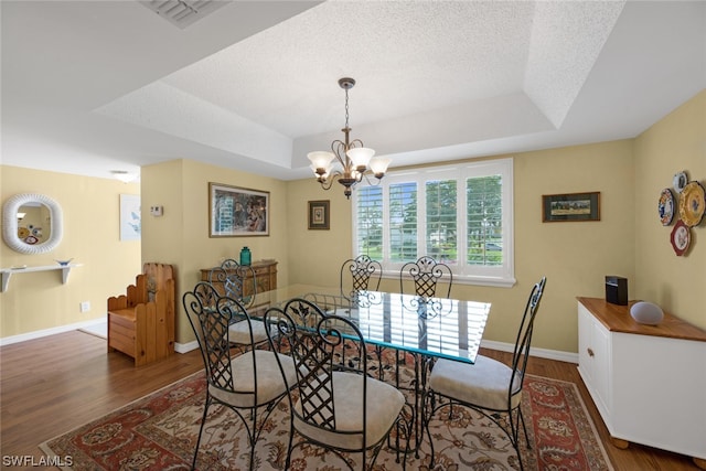 dining room featuring a raised ceiling, dark wood-type flooring, and a chandelier