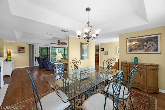 dining room with ceiling fan with notable chandelier, a raised ceiling, and dark hardwood / wood-style floors