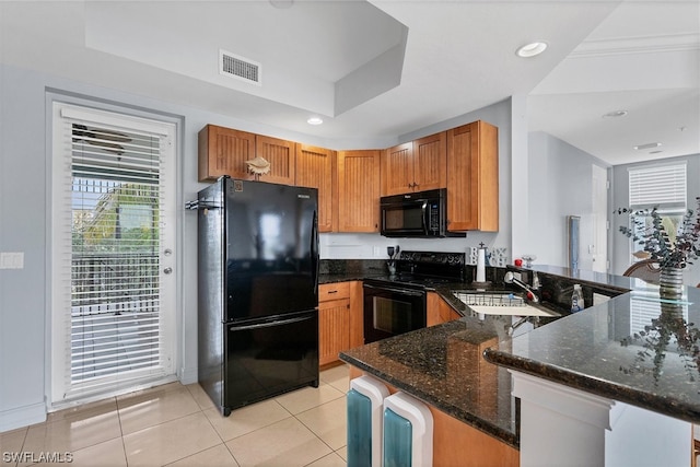 kitchen with kitchen peninsula, a tray ceiling, black appliances, sink, and dark stone counters