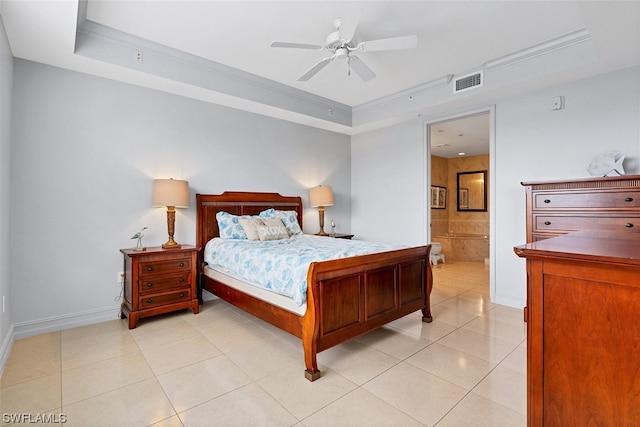 tiled bedroom featuring a tray ceiling, ensuite bath, and ceiling fan