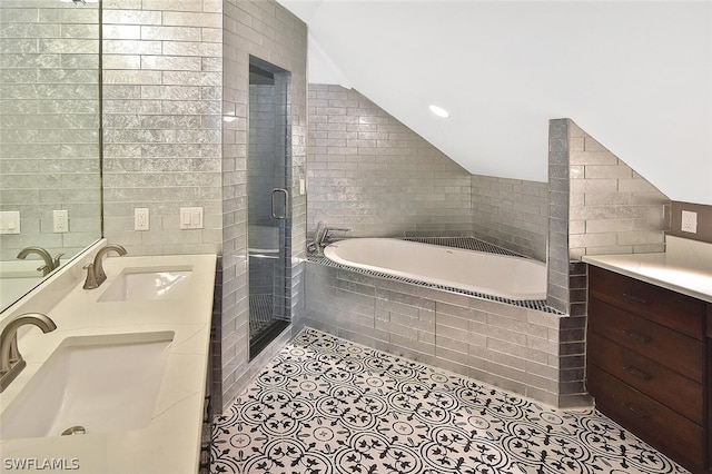 full bathroom with tile walls, vaulted ceiling, a sink, and tile patterned floors