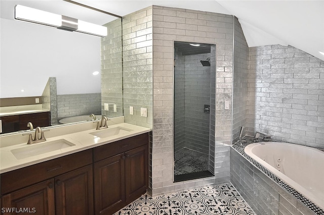 bathroom featuring shower with separate bathtub, vaulted ceiling, tile walls, vanity, and tile patterned flooring