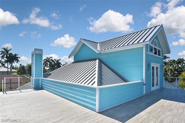 view of property exterior featuring a deck, metal roof, french doors, and a standing seam roof