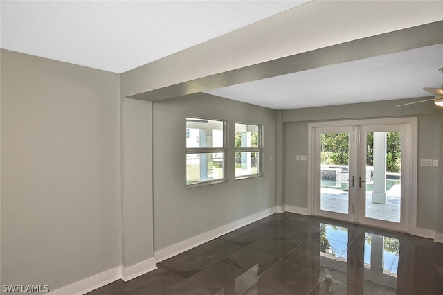 spare room featuring dark tile patterned flooring, french doors, and baseboards