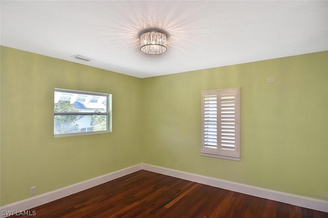 empty room with visible vents, dark wood finished floors, and baseboards