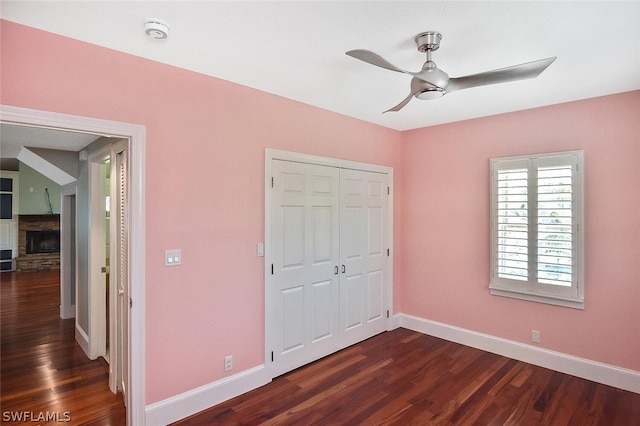 unfurnished bedroom with dark hardwood / wood-style flooring, a fireplace, a closet, and ceiling fan