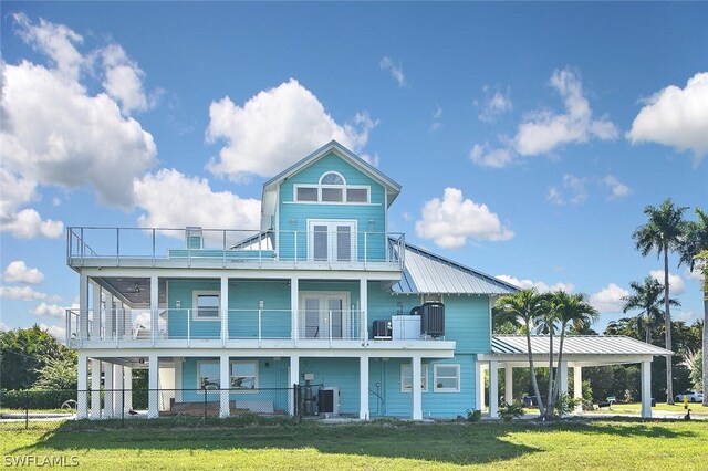 back of house featuring a balcony, a yard, and central air condition unit