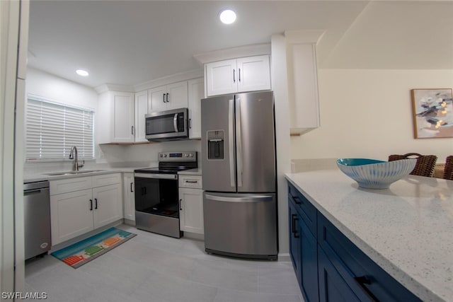 kitchen with sink, light tile floors, light stone counters, white cabinets, and appliances with stainless steel finishes