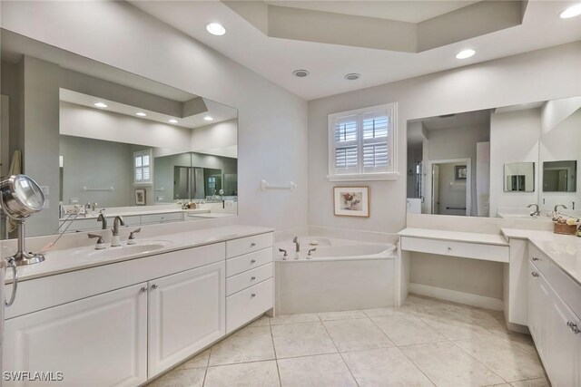 bathroom with vanity, tile patterned flooring, a tray ceiling, and a tub