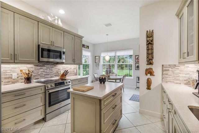 kitchen featuring decorative light fixtures, light stone countertops, appliances with stainless steel finishes, and tasteful backsplash