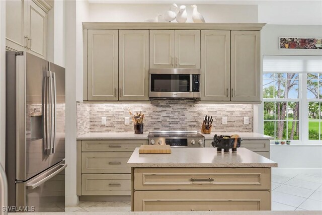 kitchen featuring decorative backsplash, stainless steel appliances, cream cabinetry, and light tile patterned flooring