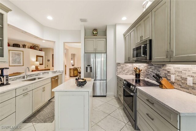 kitchen with stainless steel appliances, backsplash, a center island, light tile patterned flooring, and sink