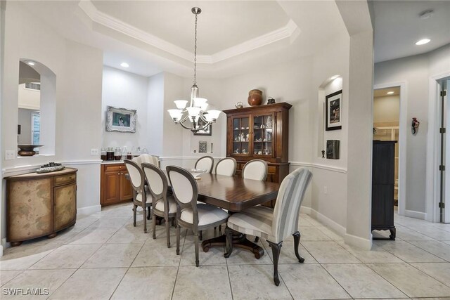 tiled dining space with a tray ceiling, ornamental molding, and a notable chandelier