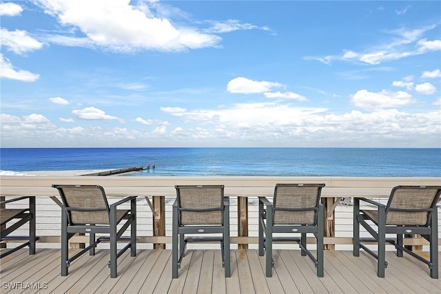 wooden terrace featuring a water view and a view of the beach