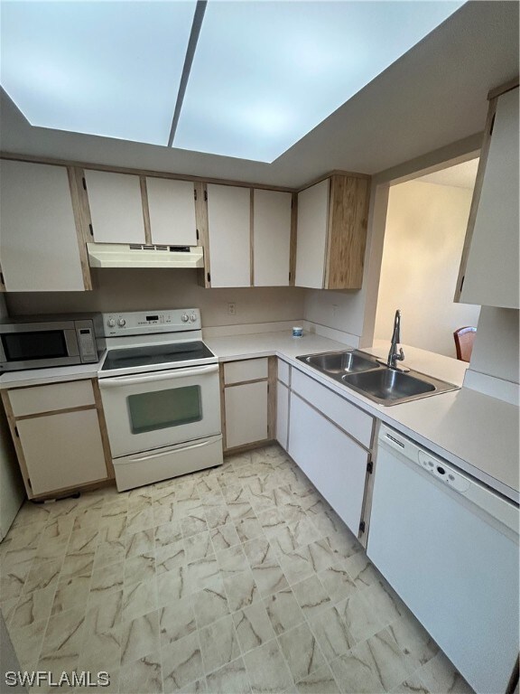 kitchen with white appliances, white cabinetry, sink, and light tile floors