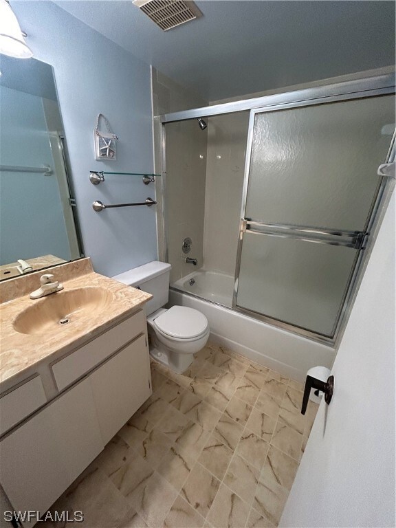 full bathroom featuring vanity, shower / bath combination with glass door, tile flooring, and toilet