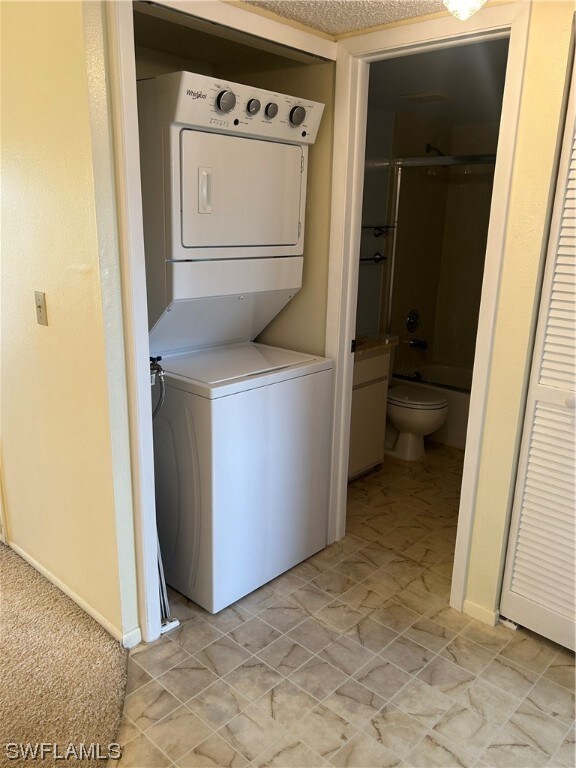 washroom with light tile floors and stacked washer and clothes dryer