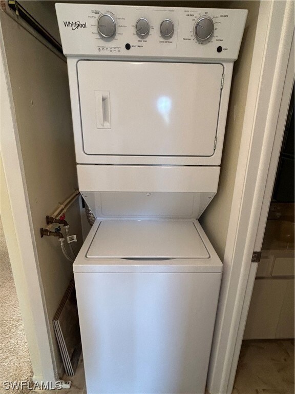 washroom with tile floors and stacked washing maching and dryer